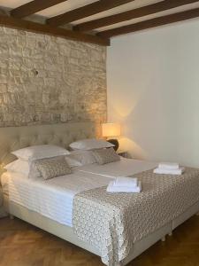 1 dormitorio con 1 cama grande y pared de piedra en Palace Wall Residences, en Split