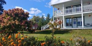 a white house with a garden in front of it at Au Coeur des Jardins in Compton
