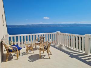 drie stoelen en een tafel op een balkon met uitzicht op het water bij Apartman Dalmatia in Duće