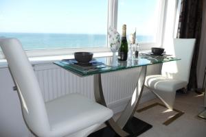 een glazen tafel met 2 stoelen en een tafel met een raam bij Hove Actually with spectacular sea views in Hove