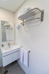een witte badkamer met een wastafel en een spiegel bij Casa da Ponte Velha in Termas de Sao Pedro do Sul