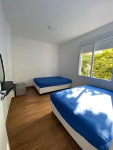 a bedroom with two beds and a window at Apartamento Guarujá Pitangueiras 50 metros da Praia. in Guarujá +7 photos