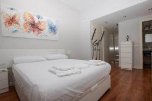 una camera bianca con un grande letto bianco con asciugamani di Apartamento completo - Centro de Algeciras a Algeciras