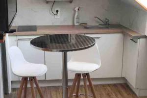 a kitchen with two white chairs and a table at charmant studio bord de mer in Menton +6 photos