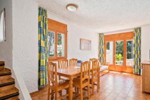 a dining room with a wooden table and chairs at Rentalmar El Pinar Adosados in Miami Platja