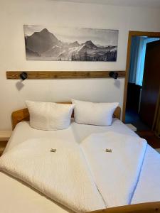 a bed with two white pillows and a painting on the wall at Apart Larcher in Arzl im Pitztal