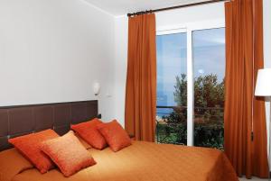 a bedroom with a bed with orange pillows and a window at Residence Villa Beuca in Cogoleto