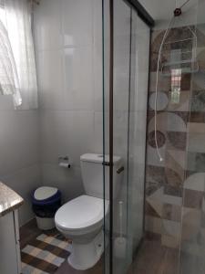 a bathroom with a toilet and a glass shower at temporada praia do forte cabo frio in Cabo Frio