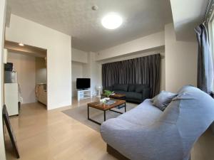 a living room with a couch and a table at Downtown area Spacious cozy room Susukino IK501 in Sapporo