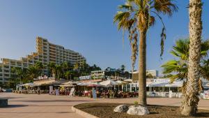 une plage avec des palmiers, des tables et des bâtiments dans l'établissement Luxury apt 1 MINUTE from the Beach of the Dunes, à Playa del Ingles