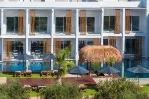 a hotel with tables and umbrellas in front of a building at Sensus Experience by Lavris in Gouves