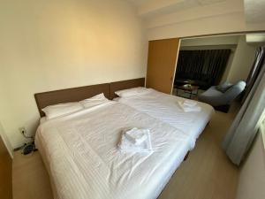 a large white bed with a white robe on it at Downtown area Spacious cozy room Susukino IK501 in Sapporo