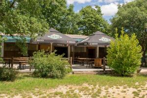 ein Restaurant mit Tischen und Sonnenschirmen in einem Park in der Unterkunft Bikers camp in Poreč