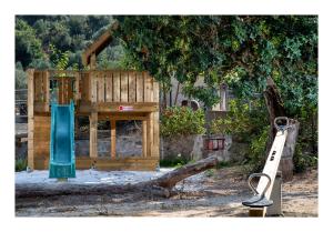 a wooden playground with a slide and a tree at Enagron Ecotourism Village in Axós