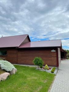 a building with a red roof and a grass yard at Sodyba "Kristina" in Biržai