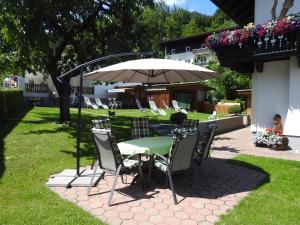 einen Tisch und Stühle unter einem Regenschirm im Hof in der Unterkunft Pension Alpenrose in Zell am See