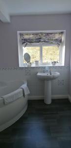 baño con bañera, lavabo y ventana en Newby Cross en Carlisle