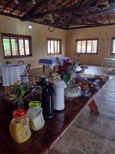 a long wooden table with flowers and jars on it at Espaço Mascattes Pousada in Serra do Cipo