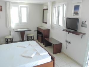 Habitación blanca con cama y TV en Mama's Rooms - Eurostudiosnaxos, en Naxos Chora