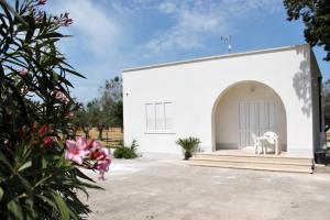 un edificio bianco con portico e sedia bianca di Dimora Rem Country Life a 2 minuti dal mare a Nardò