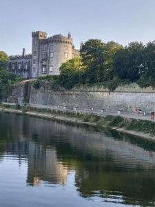 a castle sitting on the side of a river at Castle Lodge Kilkenny in Kilkenny