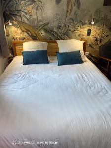 ein großes weißes Bett mit zwei blauen Kissen darauf in der Unterkunft Le rocher in Antibes + 42 Fotos
