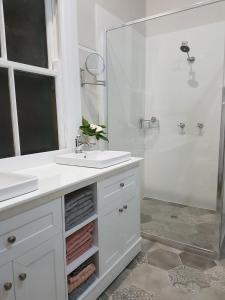 a white bathroom with a sink and a shower at Anglesey House Iconic Forbes CBD Heritage Home in Forbes