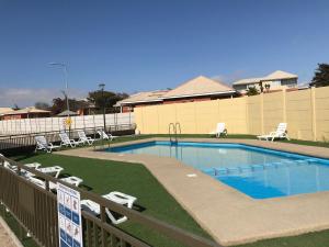 a large swimming pool with chairs and a fence at Departamento Portal Caldera in Caldera