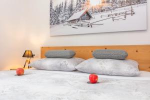 a bed with two pillows and a picture of a cabin at Apartmenthaus Maximilian in Neukirchen am Großvenediger