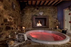 a large bath tub in a room with a fireplace at PALAZZO DEL CAPITANO Wellness & Relais - Luxury Borgo Capitano Collection in San Quirico dʼOrcia
