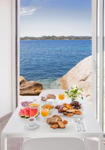 - une table blanche avec des aliments pour le petit-déjeuner sur la vue sur l'eau dans l'établissement Il Gabbiano, à La Maddalena