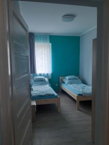 two beds in a room with blue walls at ALFA Szálláshely in Sándorfalva