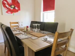 een houten tafel met zwarte stoelen en een tafel met wijnglazen bij Northolme in Filey