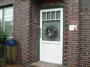 eine weiße Tür auf einem Backsteinhaus mit einem Kranz in der Unterkunft Ferienwohnung Zum grünen Holz in Bohlenberge