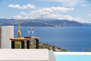 eine Flasche Wein und zwei Gläser auf einem Tisch neben dem Wasser in der Unterkunft Olon Villa in Schinias