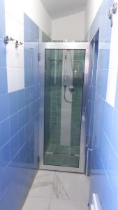 La salle de bains est pourvue d'une douche en verre avec du carrelage bleu. dans l'établissement Azzurra, à Pizzo