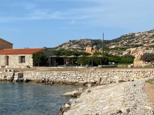 a river with a stone wall next to a building at Appartamento il Paguro a Cala Francese in La Maddalena +6 photos