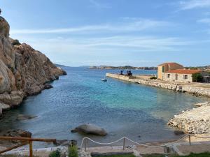 a body of water with people standing on a dock at Appartamento il Paguro a Cala Francese in La Maddalena