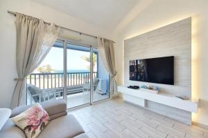 Lidia & Paco Home two bedrooms beachfront في Playa del Aguila: غرفة معيشة مع أريكة وتلفزيون وشرفة