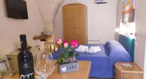 een woonkamer met een blauw bed en een fles wijn bij La Volta del Conte-Holiday Home Centro Storico in Cisternino