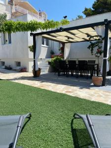 eine Terrasse mit einem Tisch und Stühlen unter einem Baldachin in der Unterkunft Modern apartment with an outdoor jacuzzi in Brodarica