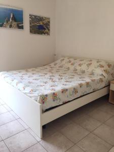 białe łóżko w pokoju z narzutą z kwiatami w obiekcie Buggerru fuori dal tempo w mieście Buggerru