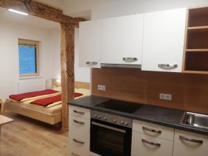 a kitchen with a stove top oven next to a bed at Ferienhof Gindl und Gästehaus Gindl in Tauplitz