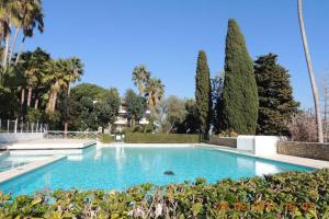 a swimming pool in a garden with palm trees at STUDIO STANDING VUE MER 2 PERS. 5 min.CANNES in Vallauris