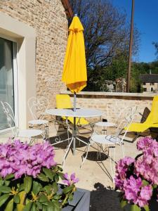 żółty parasol siedzący obok stołu i krzeseł w obiekcie Gites les écuries Saserang w mieście Mouilleron