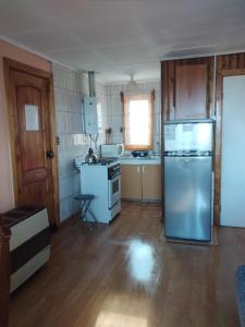 a kitchen with a refrigerator and a stove top oven at Cabañas Campestres Las Rosas in Punta Arenas