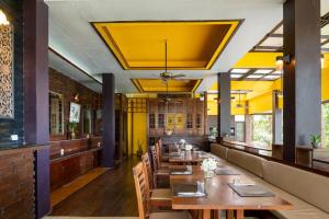 a restaurant with wooden tables and chairs and yellow ceilings at Baan Krating Khao Lak Resort - SHA plus in Khao Lak