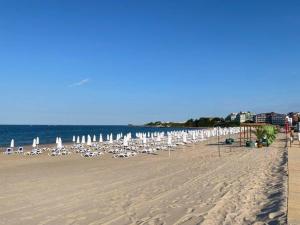 een strand met stoelen en parasols en de oceaan bij Студио Симона 3 - първа линия море in Lozenets