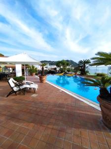 una piscina con sombrilla, mesa y silla en Dimorra Sun and Relax en Ischia