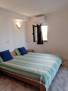 Un dormitorio con una cama grande con almohadas azules y una ventana en Studio apartment in Funtana with balcony, air conditioning, WiFi, washing machine 4982-8, en Funtana